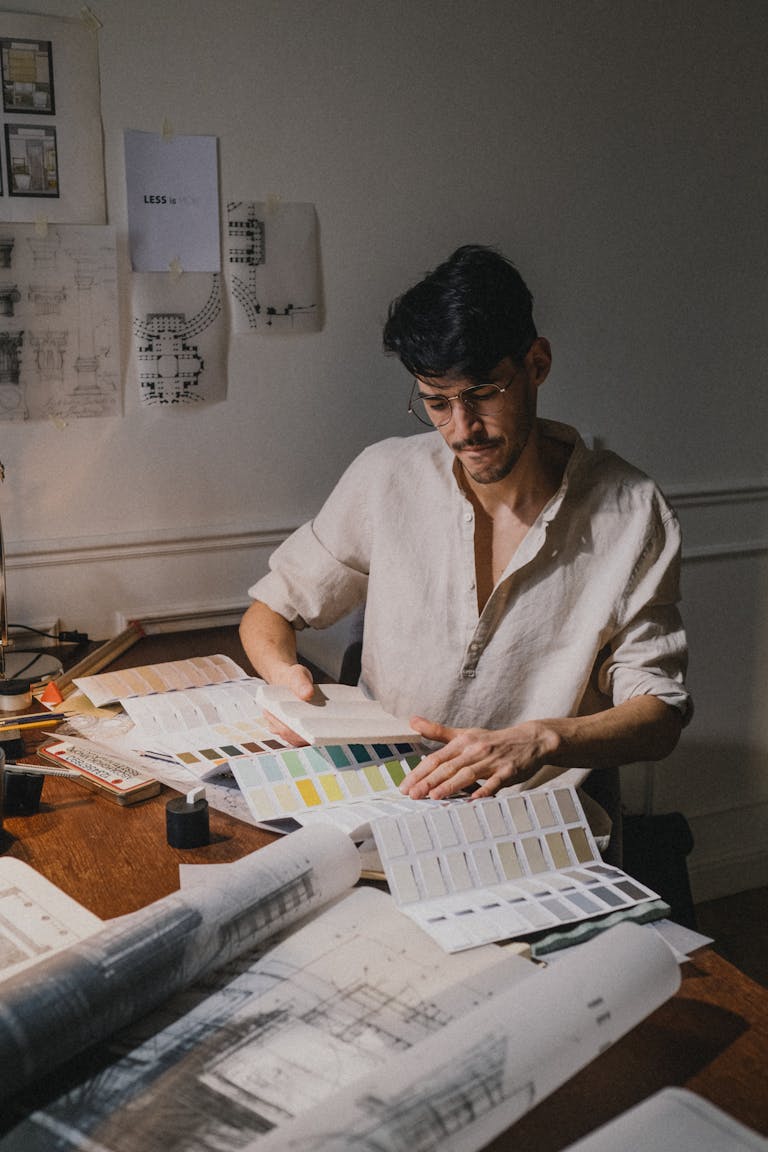 Architect deeply focused on color palette selection at workplace, creating modern designs.